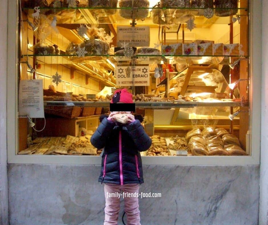 Kipper standing in front of the Jewish bakery in the Venice Ghetto, eating a slice of focaccia.