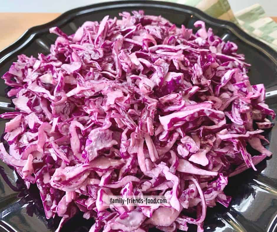 Close up of red cabbage salad in a black bowl.