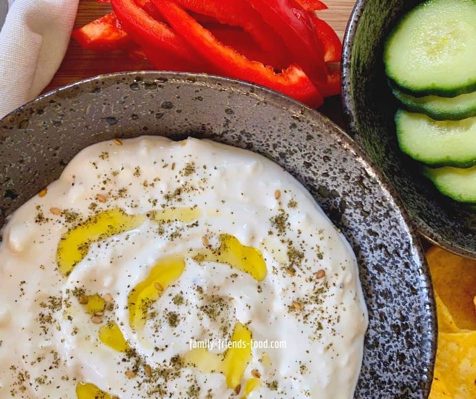 Bowl of feta cheese dip next to cucumber and pepper slices.