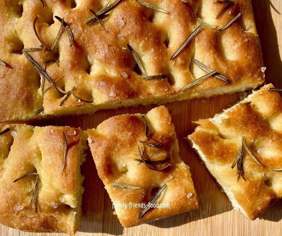 3 pieces of focaccia cut from a loaf, on a wooden board.