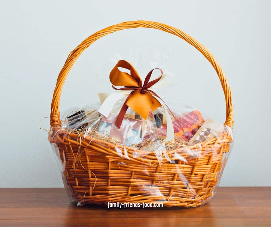 A wicker gift basket, wrapped in cellophane and tied with an orange ribbon.